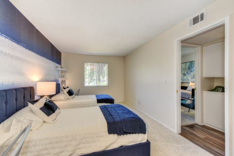 Bedroom with 2 twin beds with blue and white bedding. Washer and dryer visible in hallway